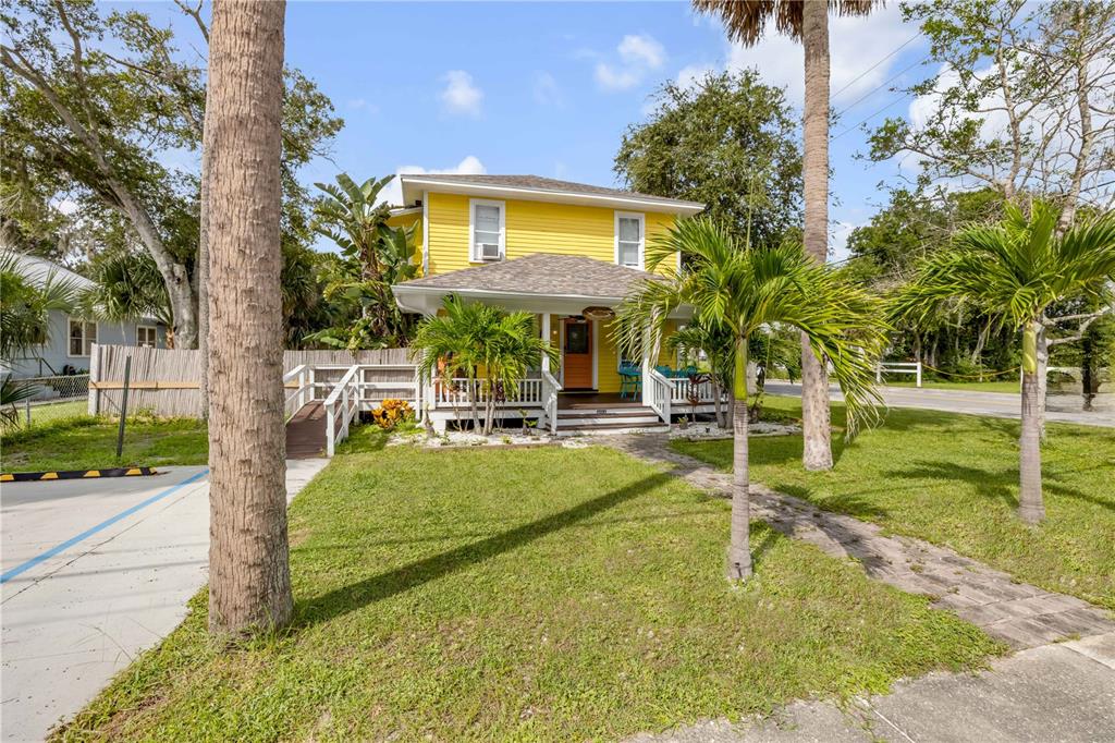 A two-story yellow house with a front porch and palm trees in the yard — 200 LIVE OAK STREET, NEW SMYRNA BEACH, FL