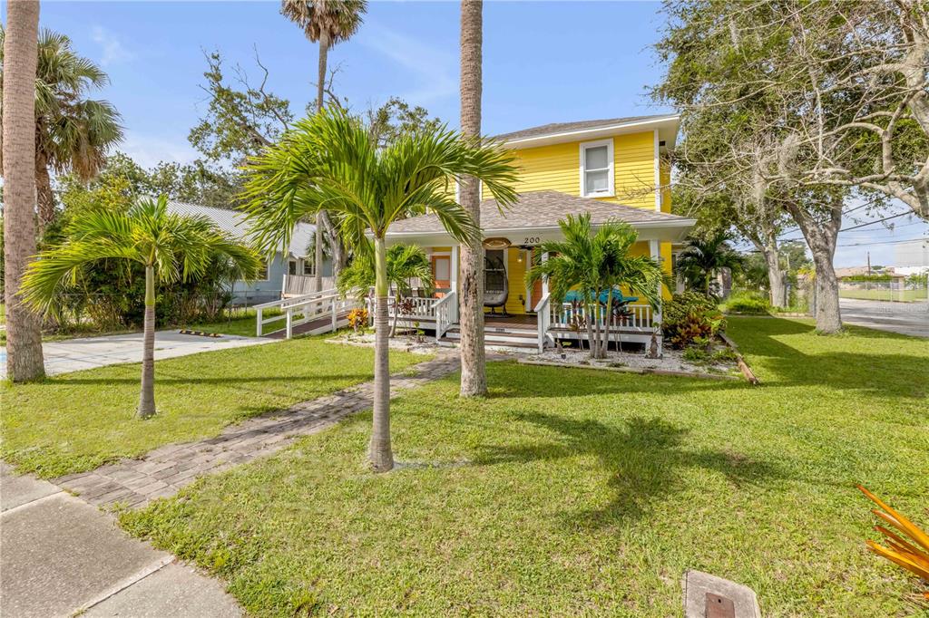 A yellow two-story house features a front porch, a wheelchair ramp, and several palm trees — 200 LIVE OAK STREET, NEW SMYRNA BEACH, FL
