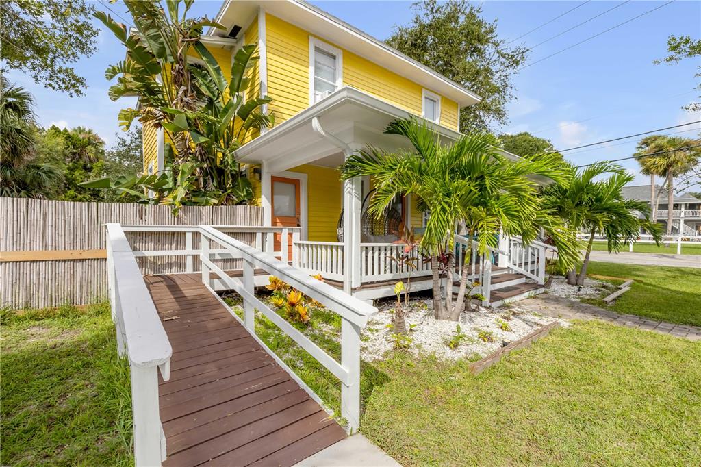 A yellow two-story house features a wooden wheelchair ramp leading to a covered front porch — 200 LIVE OAK STREET, NEW SMYRNA BEACH, FL