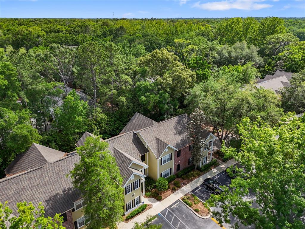 An aerial view shows a multi-story apartment building surrounded by dense trees and parking — 10000 SW 52ND AVENUE UNIT 68, GAINESVILLE, FL