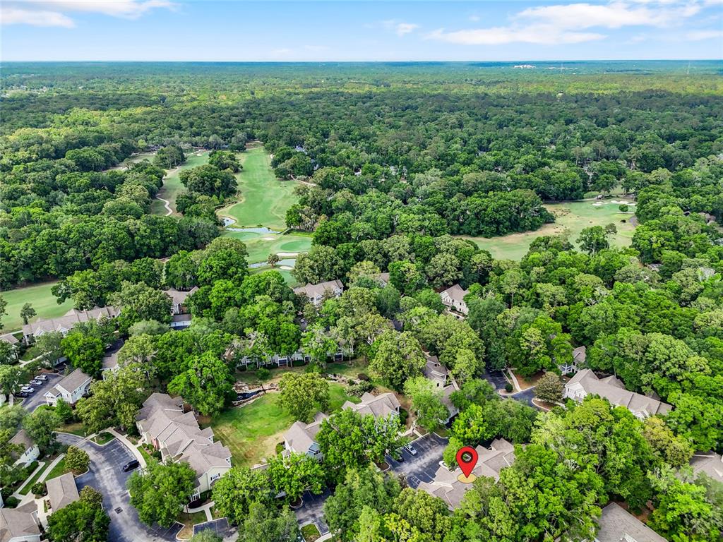An aerial view shows a residential complex surrounded by dense trees and a golf course — 10000 SW 52ND AVENUE UNIT 68, GAINESVILLE, FL