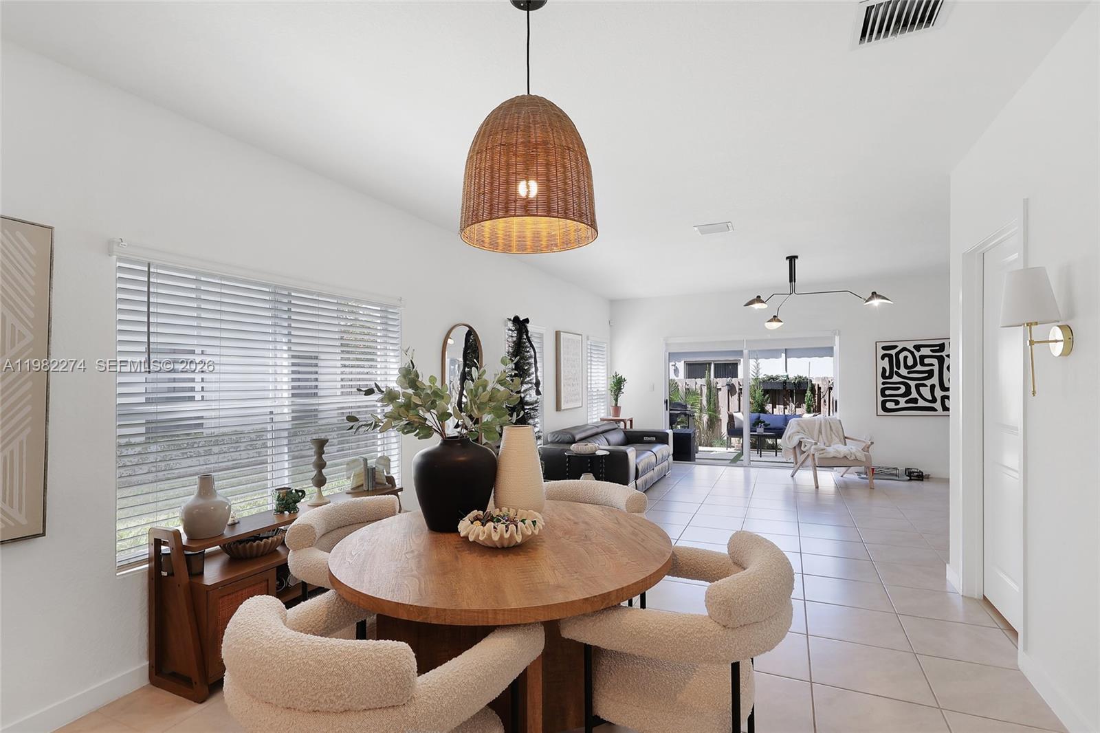 A dining area with a round wooden table and textured chairs sits before a living space — 357 NE 1st Dr, Florida City FL 33034, FLORIDA CITY, FL