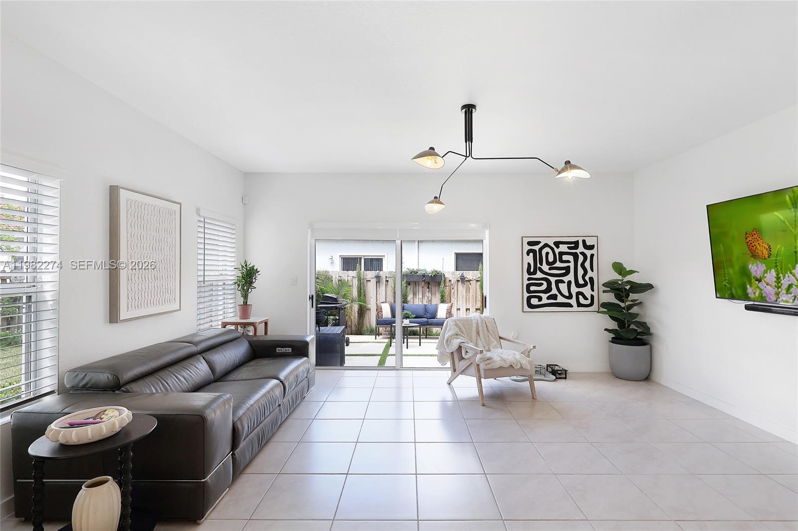 A living room features a dark leather sofa, tile flooring, and a sliding glass door — 357 NE 1st Dr, Florida City FL 33034, FLORIDA CITY, FL