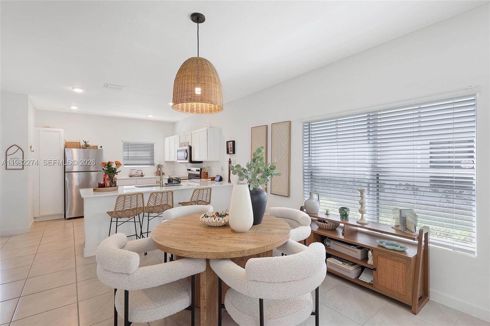 A dining area with a round wooden table and textured chairs sits near a kitchen — 357 NE 1st Dr, Florida City FL 33034, FLORIDA CITY, FL