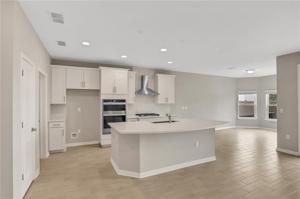 A modern kitchen with white cabinets, a large island, and light-colored tile flooring — 3852 HOLSTEIN WAY, GREEN COVE SPRINGS, FL