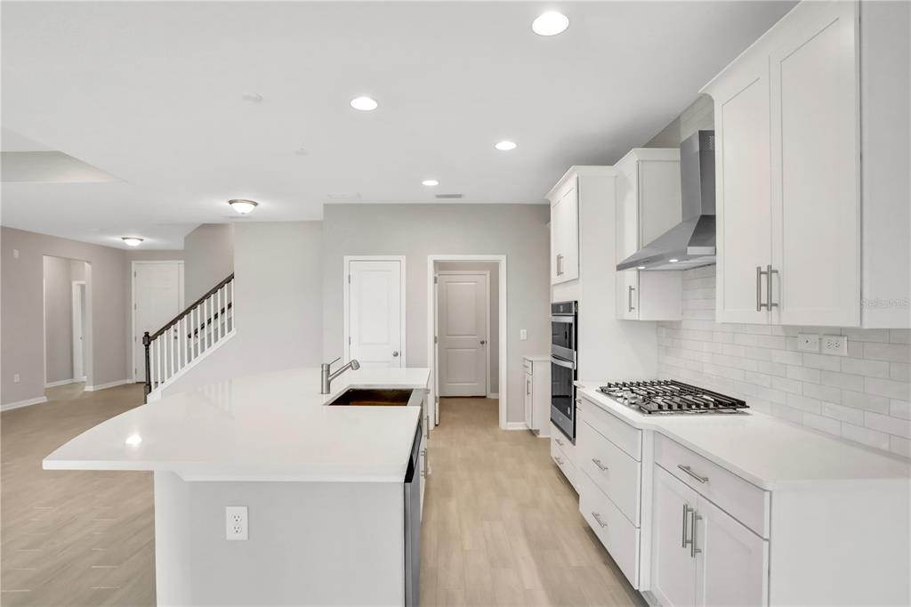 A modern kitchen features white cabinets, quartz countertops, a gas cooktop, and a center island — 3852 HOLSTEIN WAY, GREEN COVE SPRINGS, FL