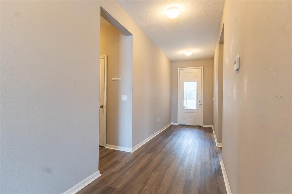 An open-concept living room, dining area, and kitchen with wood-look flooring and neutral walls — 10514 MEDFORD LAKE DRIVE, RIVERVIEW, FL