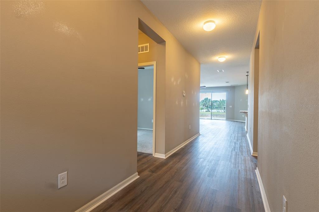 An open-concept kitchen with wood cabinets and a breakfast bar overlooks a spacious living area — 10514 MEDFORD LAKE DRIVE, RIVERVIEW, FL