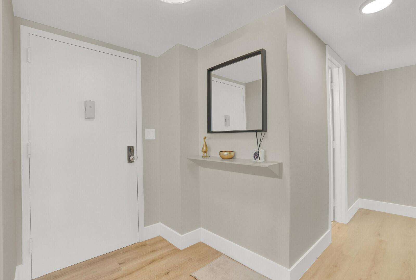 An entryway features a white door, a wall-mounted shelf with decor, and a square mirror — 1361 S Ocean Boulevard, Pompano Beach FL 33062, POMPANO BEACH, FL