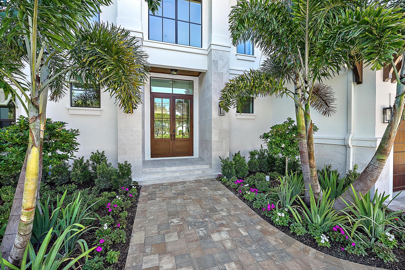 A paved walkway leads to the wooden double front doors of a modern white house — 325 Fairway N, Tequesta FL 33469, TEQUESTA, FL