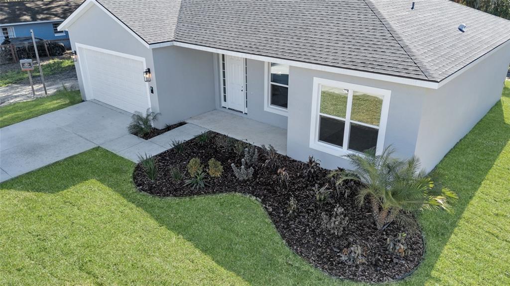 An aerial view of a gray single-story house with a garage and landscaped front yard — 902 SW 2ND STREET, OCALA, FL