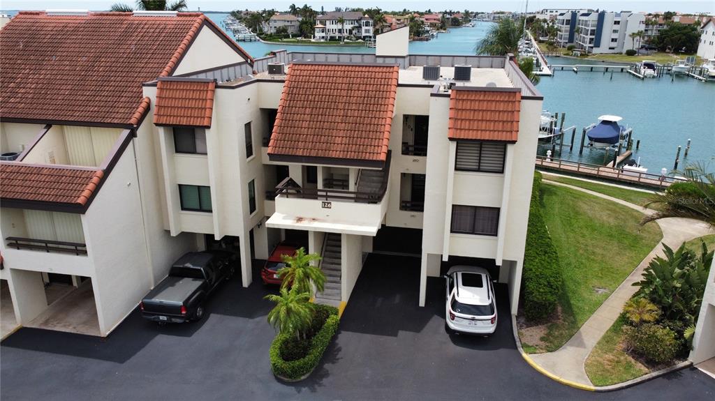 An aerial view of a multi-story residential building with a tiled roof and parking spaces — 126 1ST STREET E UNIT 210, TIERRA VERDE, FL