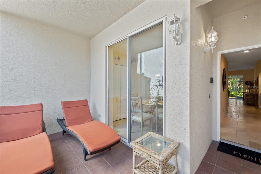 A covered patio features two lounge chairs, a small wicker table, and a sliding glass door — 9611 CASTLE POINT DRIVE UNIT 915, SARASOTA, FL