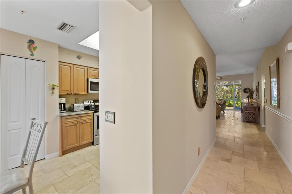 A view from a hallway looking into a kitchen with wood cabinets and tile flooring — 9611 CASTLE POINT DRIVE UNIT 915, SARASOTA, FL
