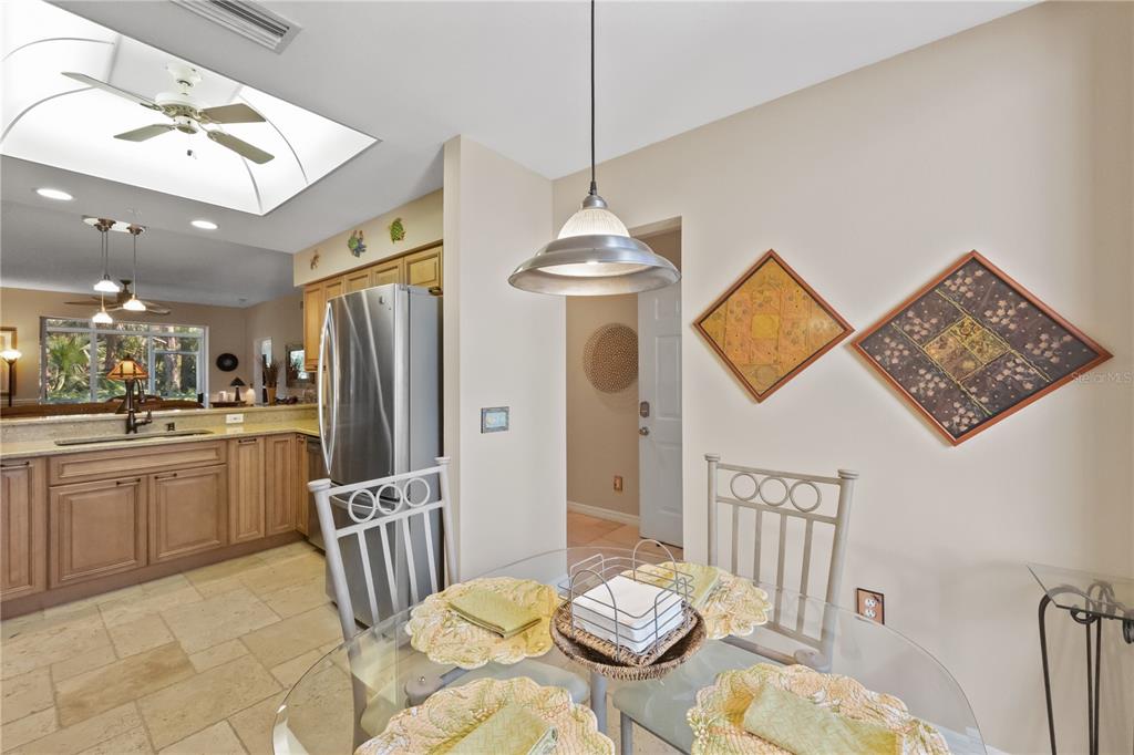 A dining area with a glass table and chairs sits adjacent to a kitchen with cabinets — 9611 CASTLE POINT DRIVE UNIT 915, SARASOTA, FL