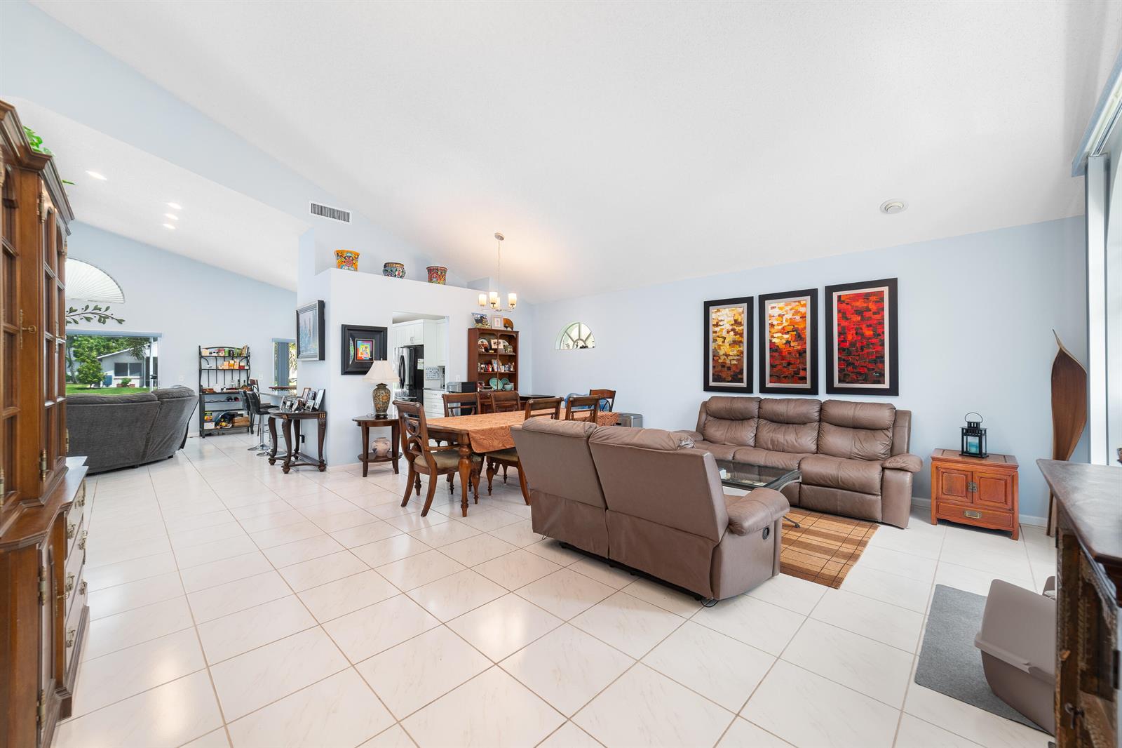 An open-concept living and dining area features light tile flooring, vaulted ceilings, and brown furniture — 2211 Soundings Court, FL 33413, FL
