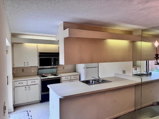 A kitchen with white cabinets, a peninsula counter, a built-in microwave, and mirrored walls — 217 Live Oak Lane, Boynton Beach FL 33436, BOYNTON BEACH, FL