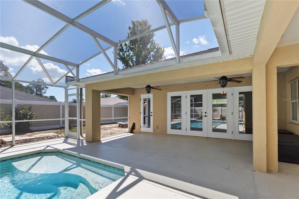 A covered patio with a pool enclosure overlooks a swimming pool and a fenced yard — 90 UNIVERSIAL TRAIL, PALM COAST, FL