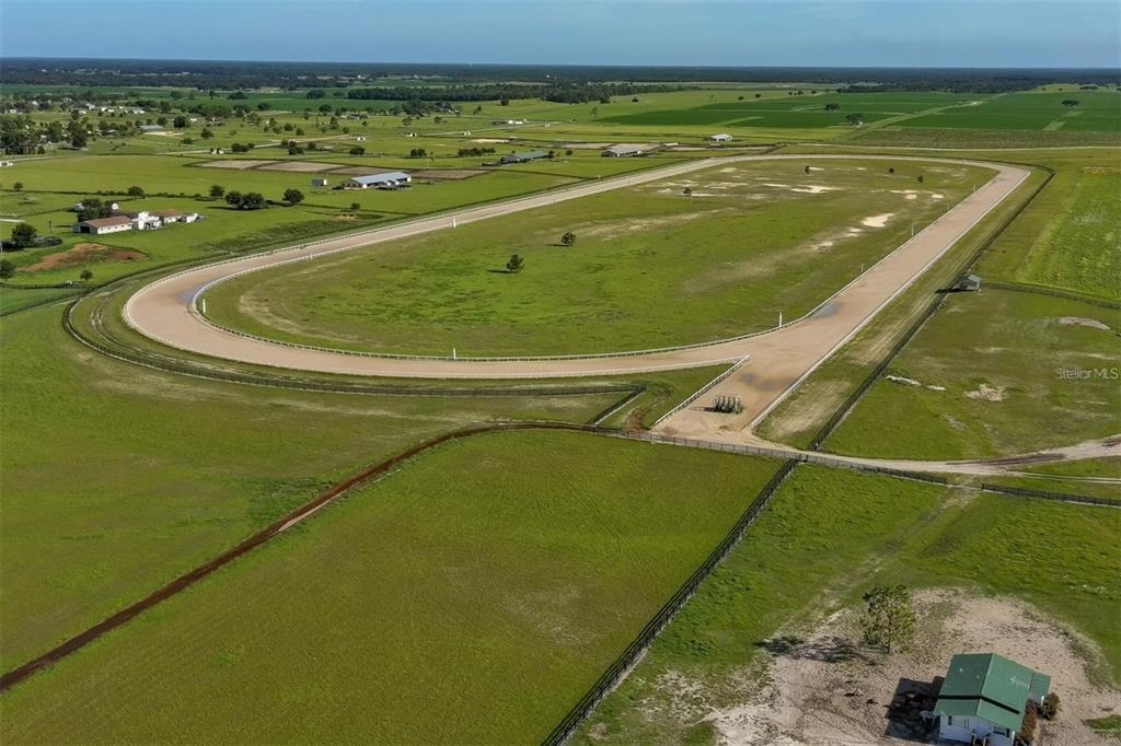 An aerial view shows a dirt horse racing track surrounded by large green pastures — 2351 NE 120 AVENUE, WILLISTON, FL