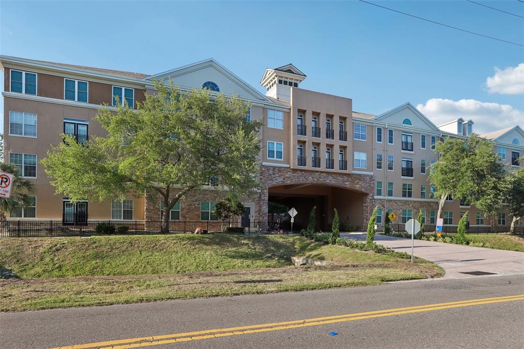 A multi-story apartment building with a stone-accented archway and a paved driveway — 4221 W SPRUCE STREET UNIT 2309, TAMPA, FL