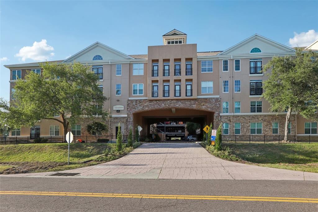 A multi-story apartment building features a stone-arched driveway entrance and a paved approach — 4221 W SPRUCE STREET UNIT 2309, TAMPA, FL