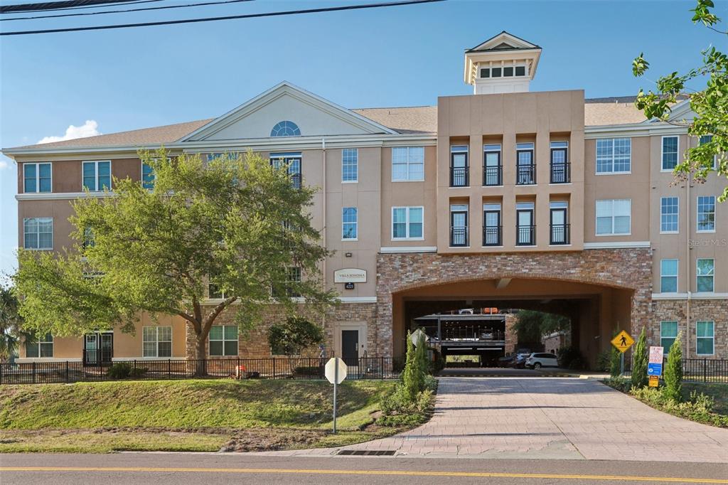 A multi-story apartment building with a stone-accented facade and an arched driveway entrance — 4221 W SPRUCE STREET UNIT 2309, TAMPA, FL