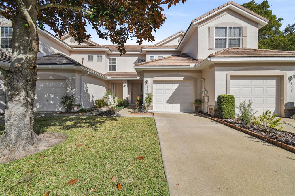 A two-story townhouse exterior features two garages, a concrete driveway, and a small front lawn — 1589 W SWEET OAKS COURT, LECANTO, FL