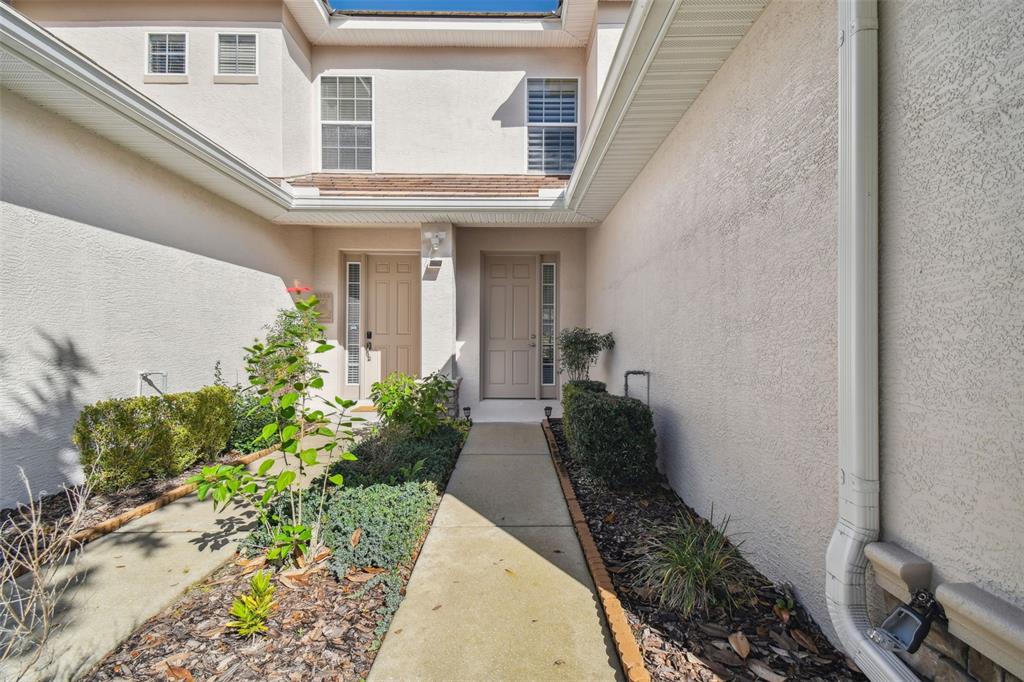 A concrete walkway leads to two tan front doors at the entrance of a home — 1589 W SWEET OAKS COURT, LECANTO, FL
