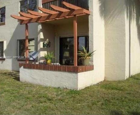 A ground-floor patio features a wooden pergola and a low brick wall — 8650 SW 149th Ave # 305, Miami FL 33193, MIAMI, FL