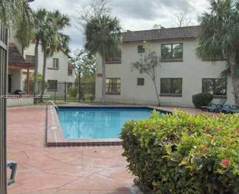 A swimming pool sits on a paved patio in front of a two-story apartment building — 8650 SW 149th Ave # 305, Miami FL 33193, MIAMI, FL