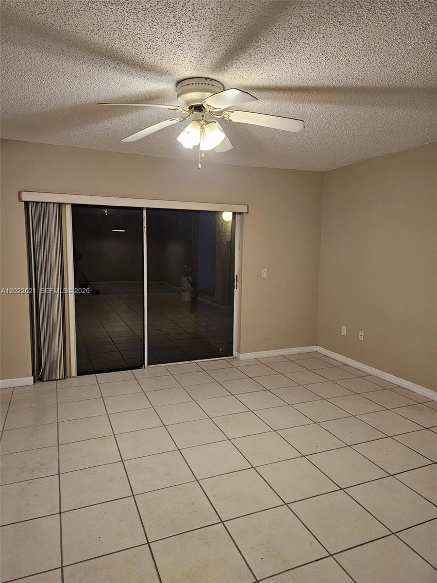 A room with beige walls, light-colored floor tiles, a ceiling fan, and sliding glass doors — 8650 SW 149th Ave # 305, Miami FL 33193, MIAMI, FL