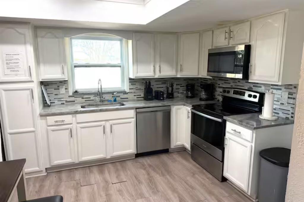 A kitchen with white cabinets, stainless steel appliances, gray countertops, and a tiled backsplash — 6506 SEAFAIRER DRIVE, TAMPA, FL