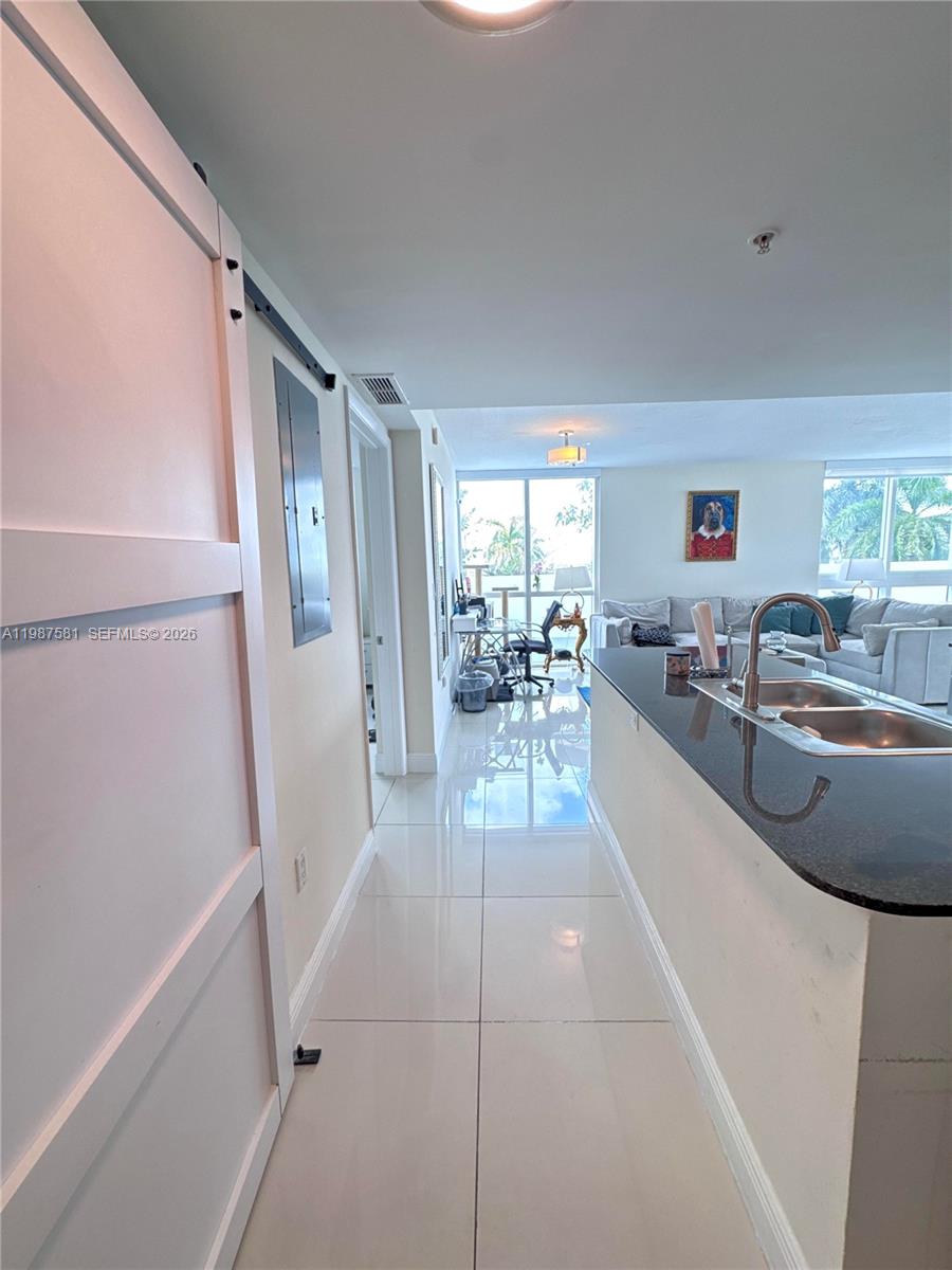 A kitchen island with a dark countertop overlooks a living area with large windows — 1861 NW S River Dr # 705, Miami FL 33125, MIAMI, FL