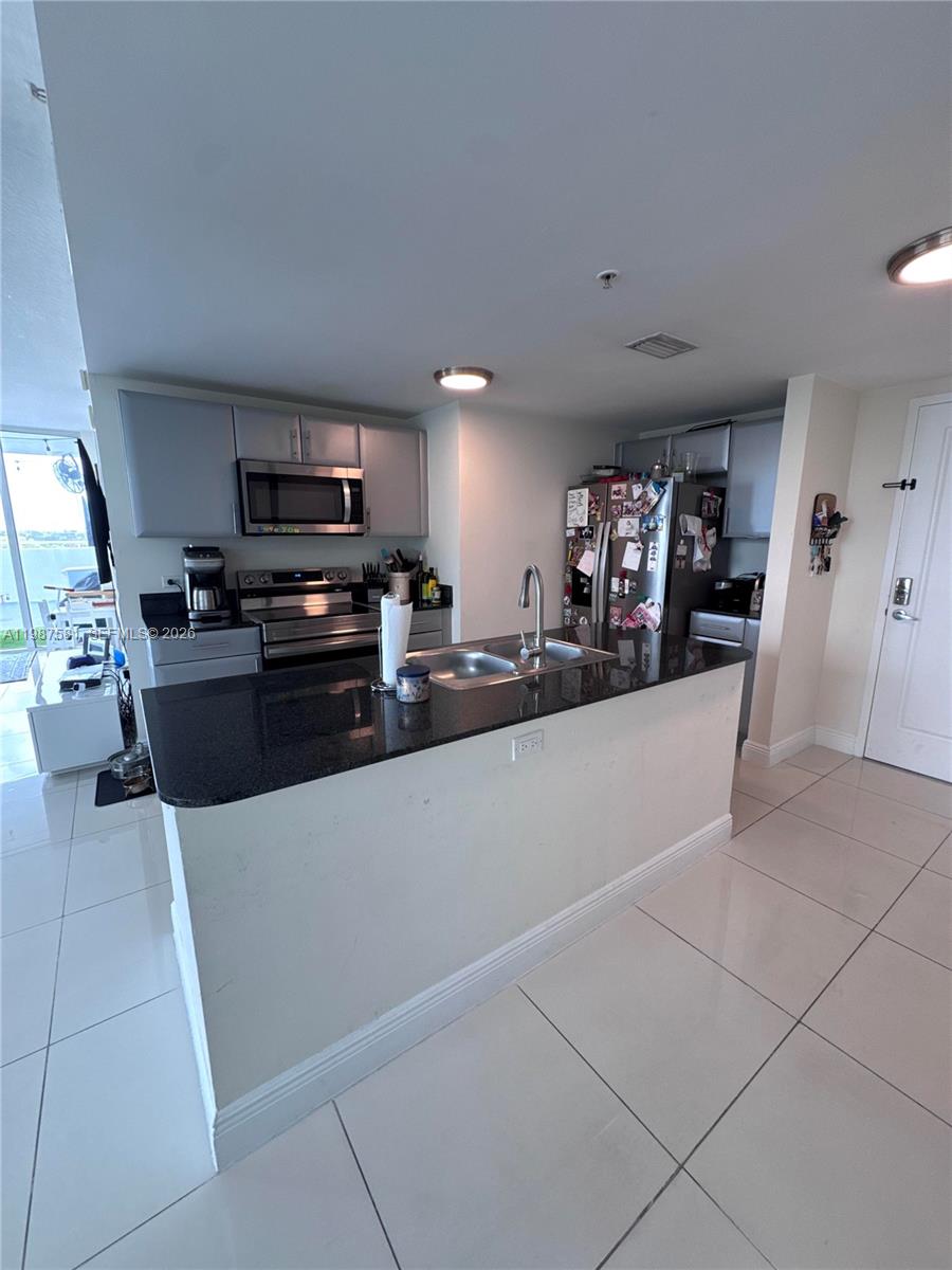 A kitchen features a black granite island, stainless steel appliances, and light-colored tile flooring — 1861 NW S River Dr # 705, Miami FL 33125, MIAMI, FL