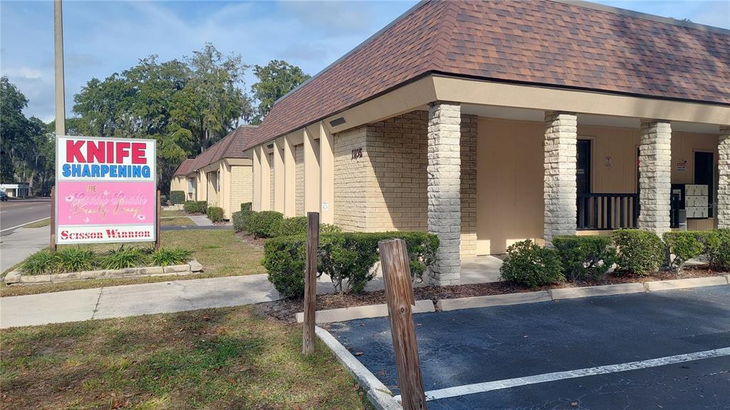 A low-rise commercial building with a brown shingled roof and a knife sharpening sign outside — 1103 NW 13TH STREET, GAINESVILLE, FL