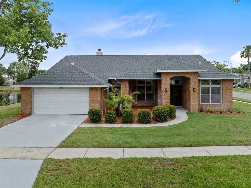 A single-story brick house with a two-car garage and a landscaped front yard — 14502 POTANOW TRAIL, ORLANDO, FL