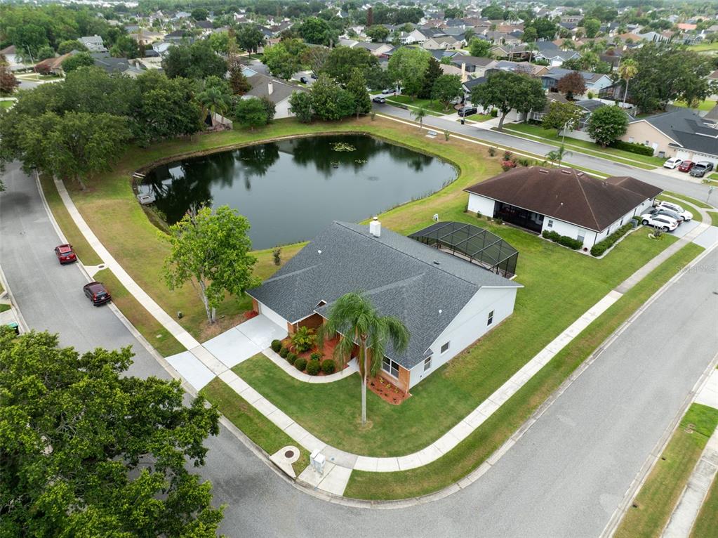 An aerial view shows a suburban house with a pool cage next to a pond — 14502 POTANOW TRAIL, ORLANDO, FL