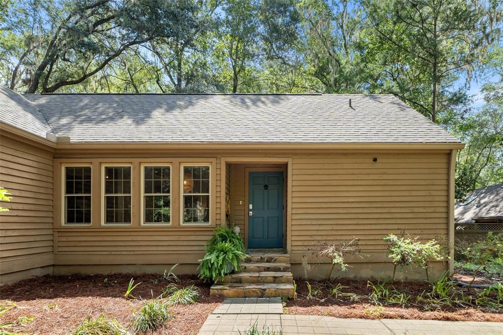 A tan-sided house with a blue front door, stone steps, and a row of windows — 5225 SW 86TH TERRACE, GAINESVILLE, FL