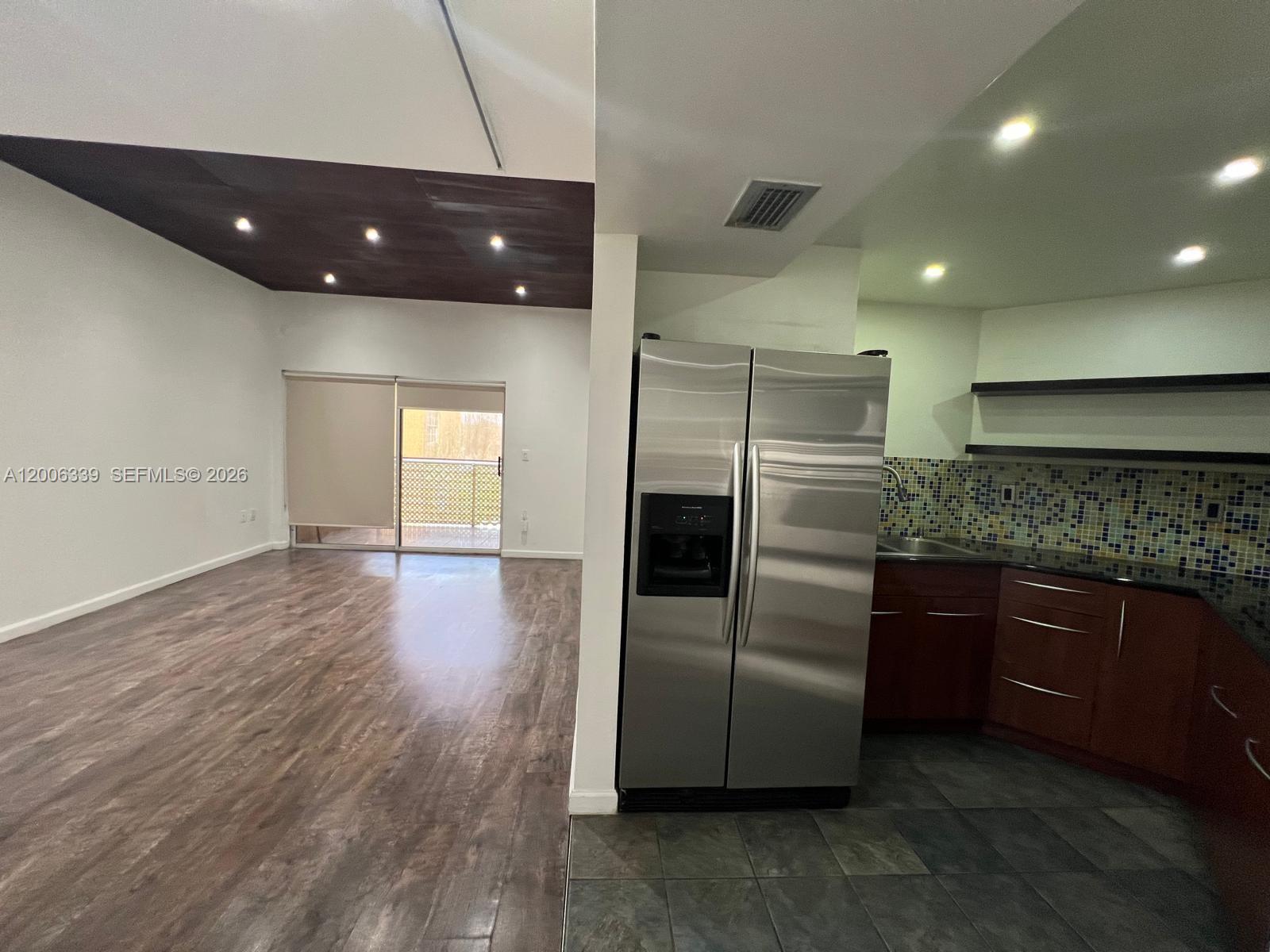 A kitchen with dark wood cabinets and a stainless refrigerator opens to a living area — 9715 Fontainebleau Blvd # E308, Miami FL 33172, MIAMI, FL
