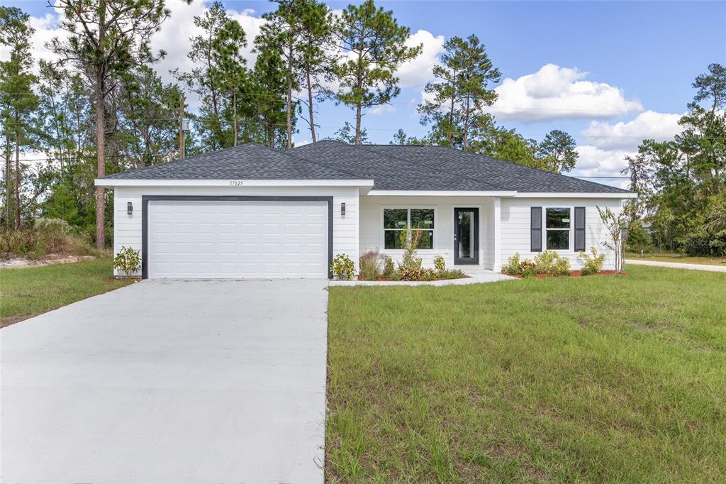 A single-story white house with a two-car garage and a concrete driveway at dusk — 15308 SW 56TH TERRACE ROAD, OCALA, FL