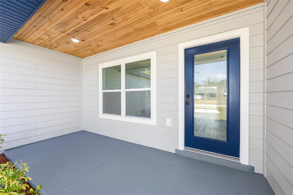 A white house exterior features horizontal siding, a dark front door, and a landscaped yard — 15308 SW 56TH TERRACE ROAD, OCALA, FL