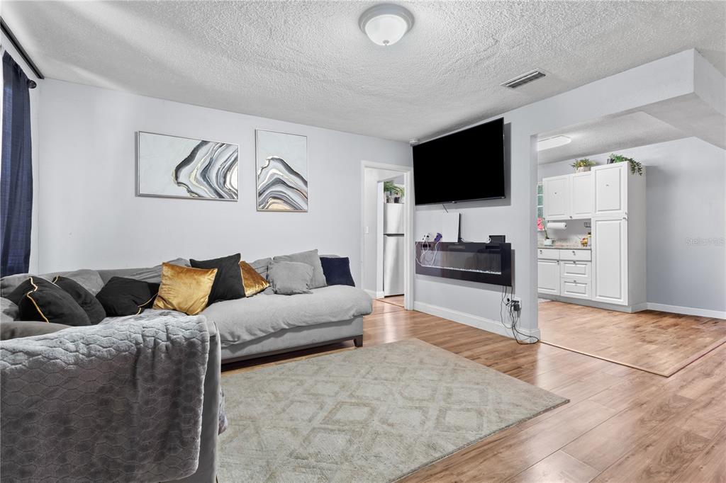 A living room features a gray sofa, a wall-mounted television, and wood-look flooring — 3918 SE 15TH STREET, GAINESVILLE, FL