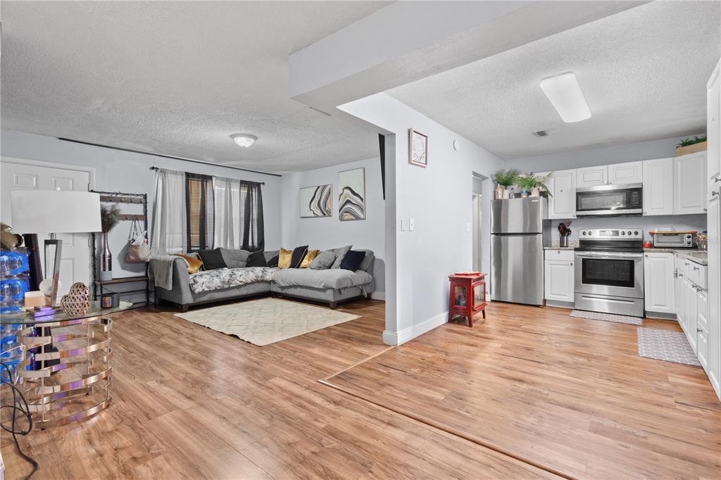An open-concept living room and kitchen featuring wood-look flooring and stainless steel appliances — 3918 SE 15TH STREET, GAINESVILLE, FL