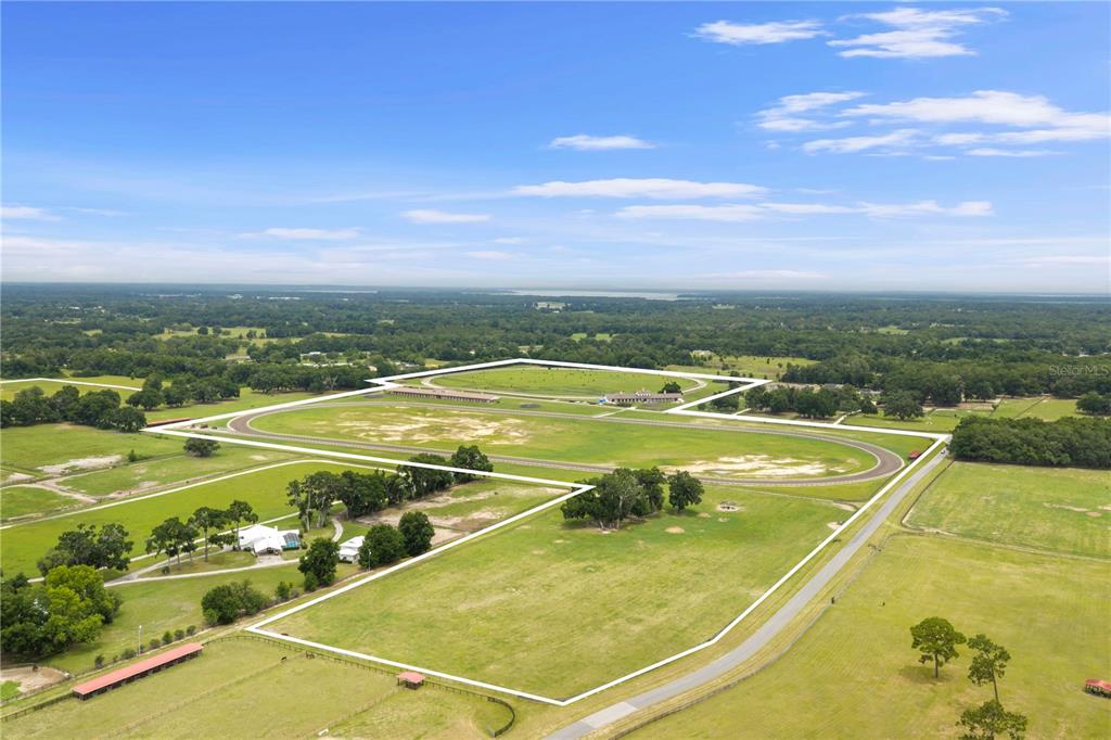 An aerial view shows a large rural property featuring a horse track and multiple buildings — 1345 NE 155TH PLACE, CITRA, FL