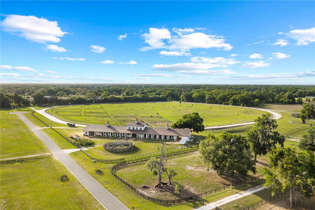 An aerial view of a horse farm featuring a long stable, paddocks, and a round pen — 1345 NE 155TH PLACE, CITRA, FL