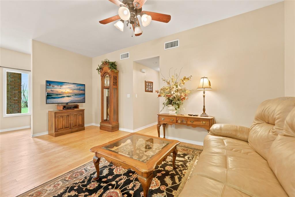 A living room features a tan leather sofa, a glass-top coffee table, and a grandfather clock — 2760 NW 105TH DRIVE, GAINESVILLE, FL
