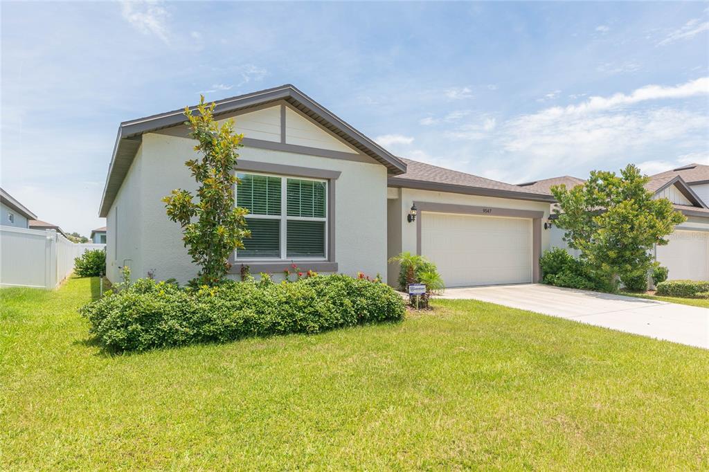 A single-story house with a beige stucco exterior, a two-car garage, and a front lawn — 9547 SUMMERS CAY CIRCLE, THONOTOSASSA, FL