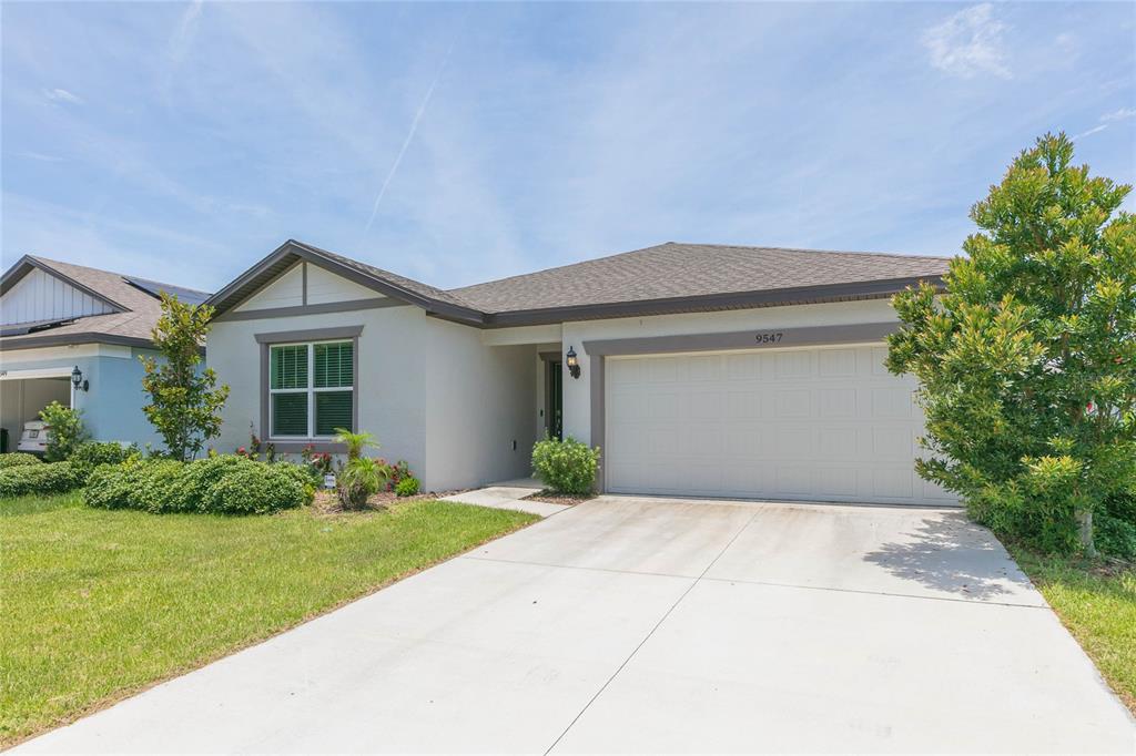 A single-story house with a white stucco exterior, a two-car garage, and a concrete driveway — 9547 SUMMERS CAY CIRCLE, THONOTOSASSA, FL