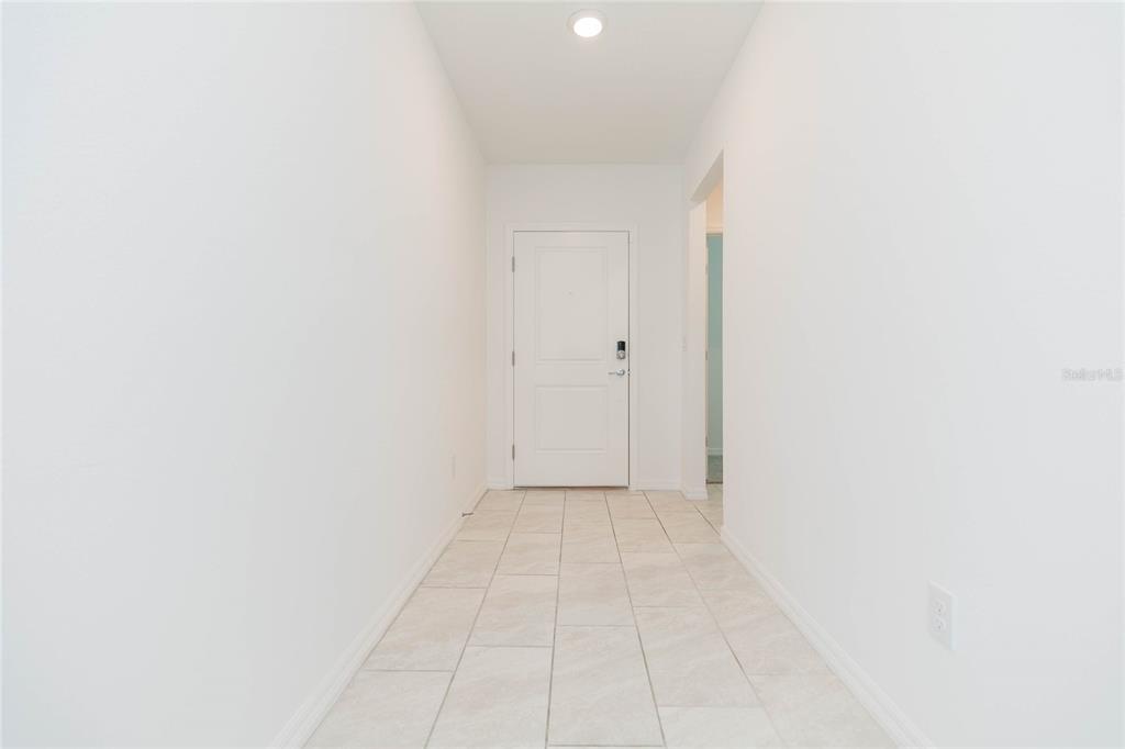 A bright entryway features white walls, a white front door, and light-colored tile flooring — 9547 SUMMERS CAY CIRCLE, THONOTOSASSA, FL