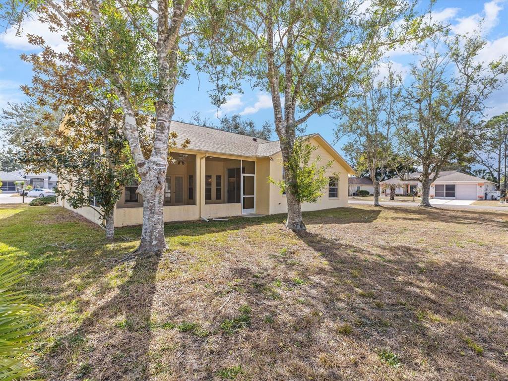 A tan single-story house with a screened-in porch sits on a grassy lot with trees — 3123 QUAIL HOLLOW COURT, SPRING HILL, FL